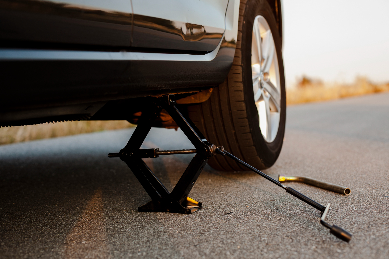 black car lifted up by jack screw